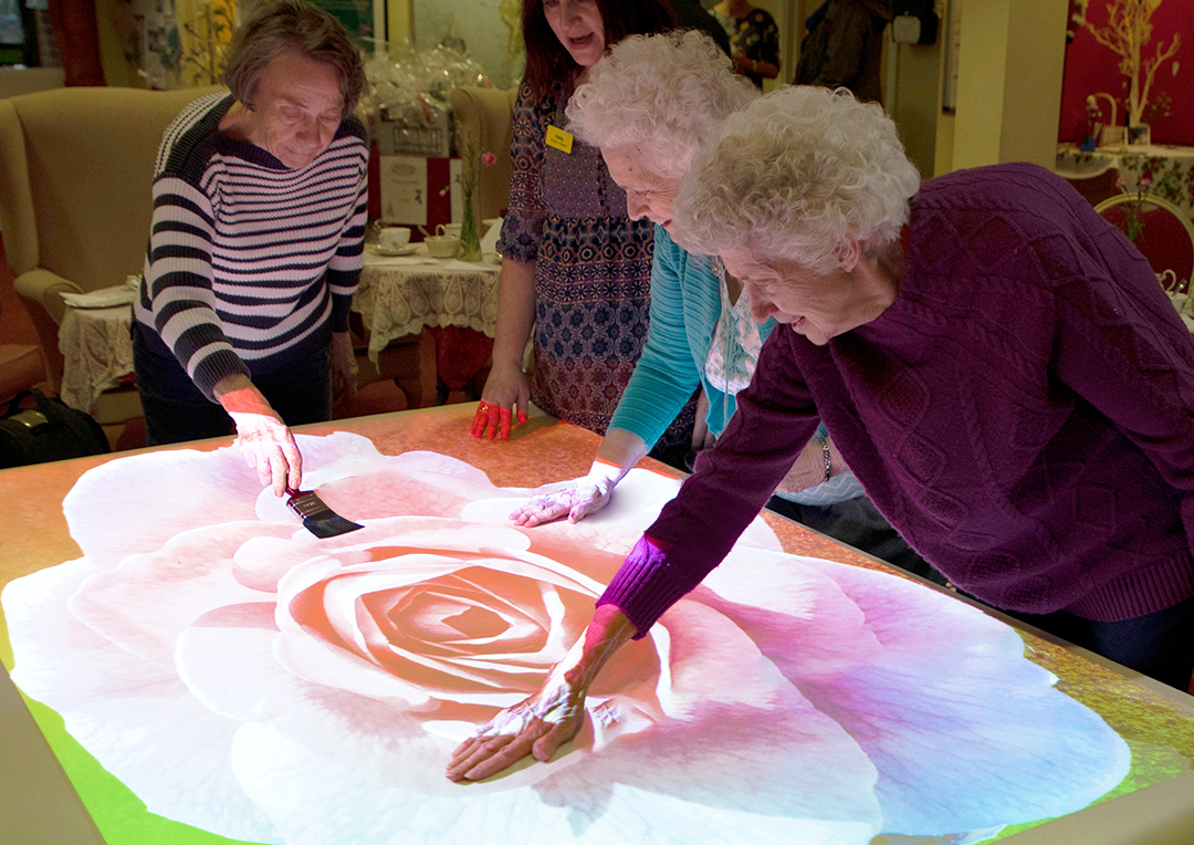 care home residents using sensory light projector activities on tabletop